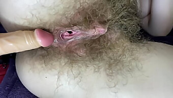 A close-up view of a hairy girl stimulating her wet and large clit with a dildo for a sexy experience